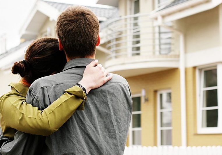 couple in front of one-family house in modern residential area
